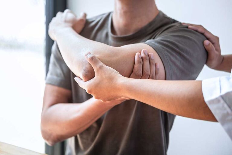 A close-up of a practitioner using a stainless steel instrument on a patient's forearm.