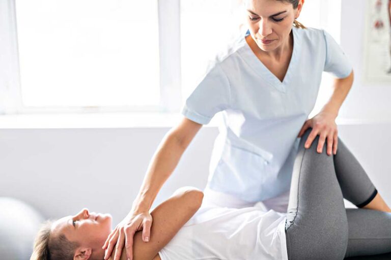 A chiropractor explains spinal wellness to an adult couple during an educational session in a comfortable office setting.