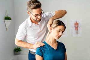A woman sitting comfortably in a chiropractor’s office discussing symptoms with a healthcare provider.